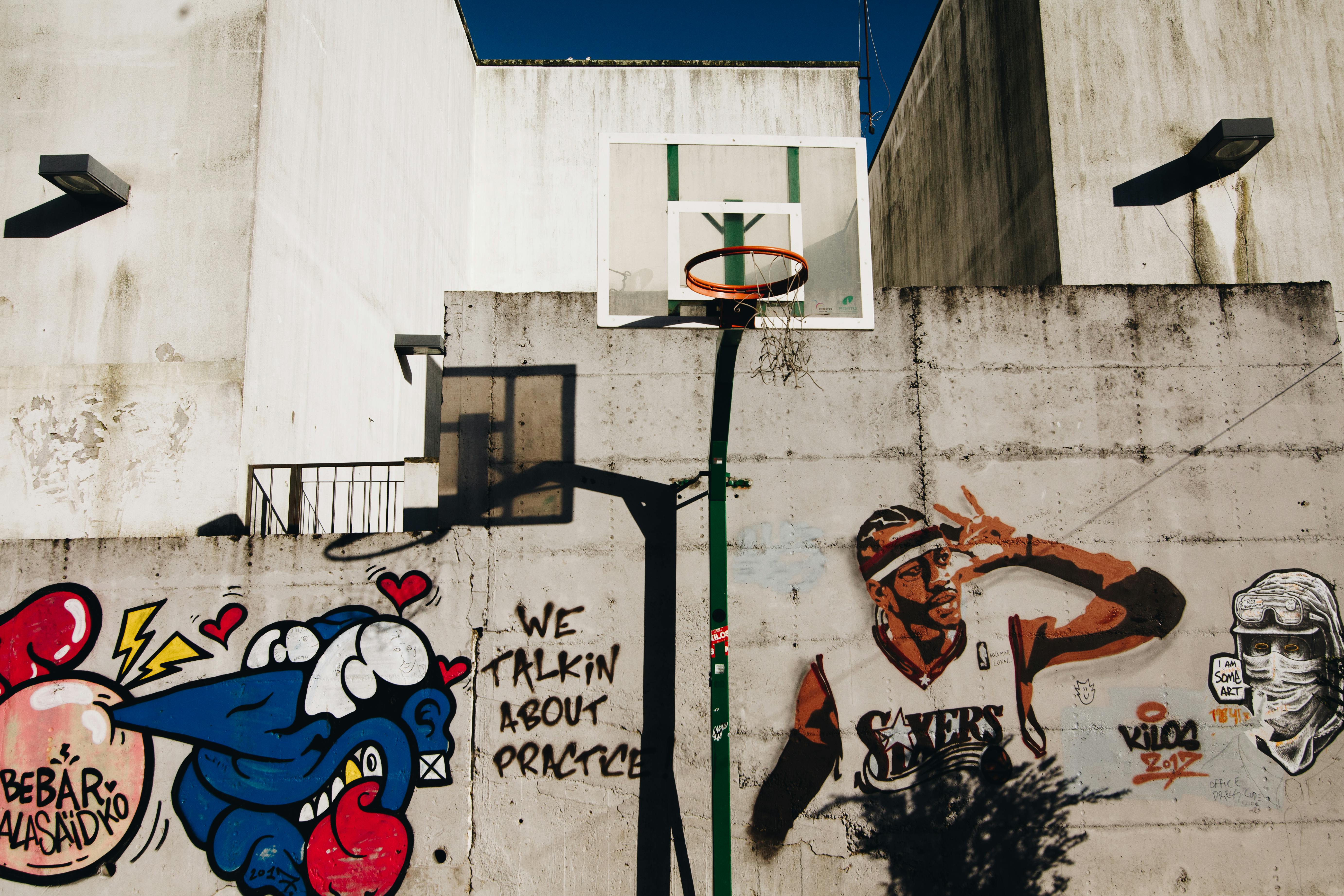 Urban basketball hoop with vibrant street art on a sunny day in Porto, Portugal.