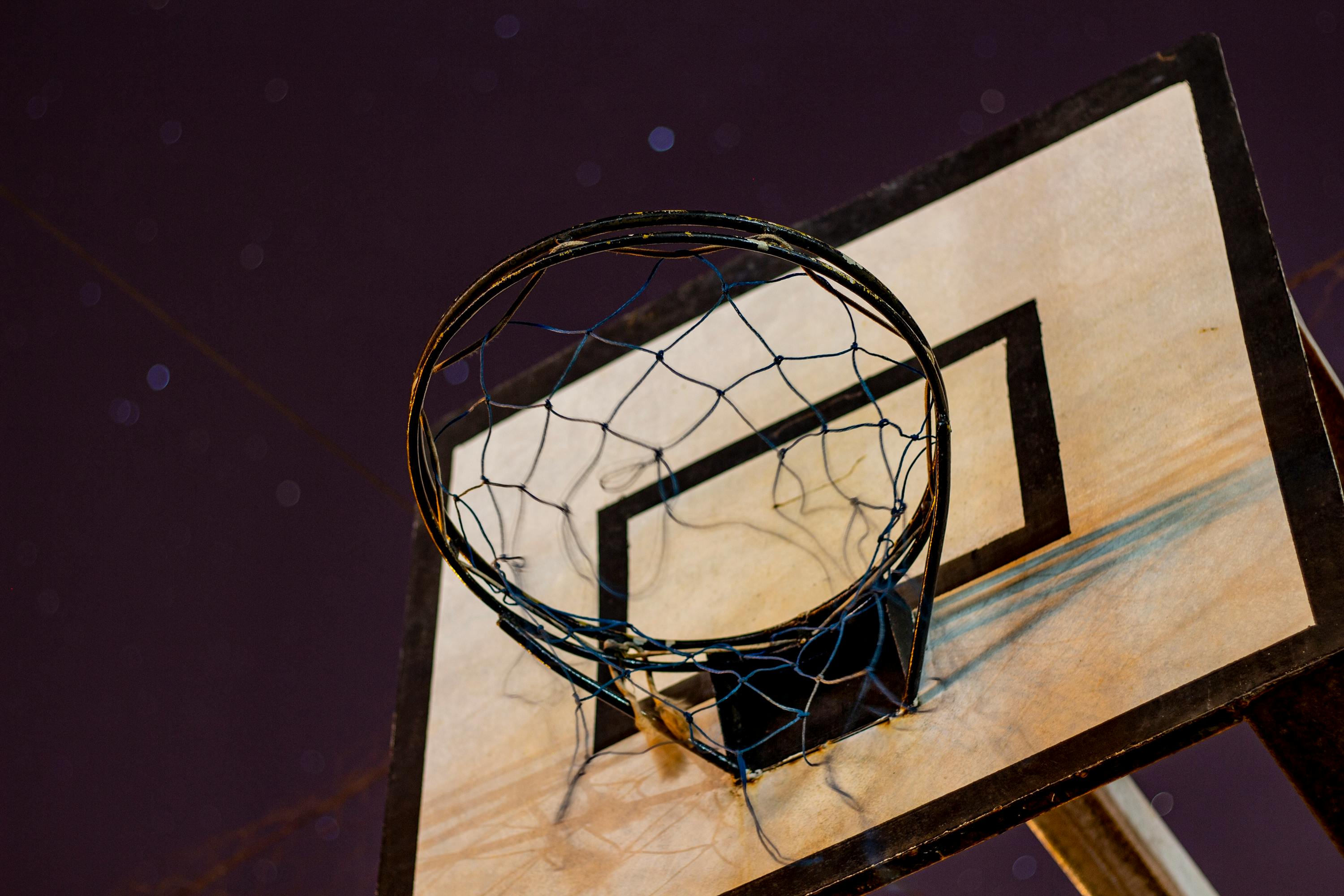 Low angle shot of a basketball hoop against a starry night sky, perfect for sports themes.