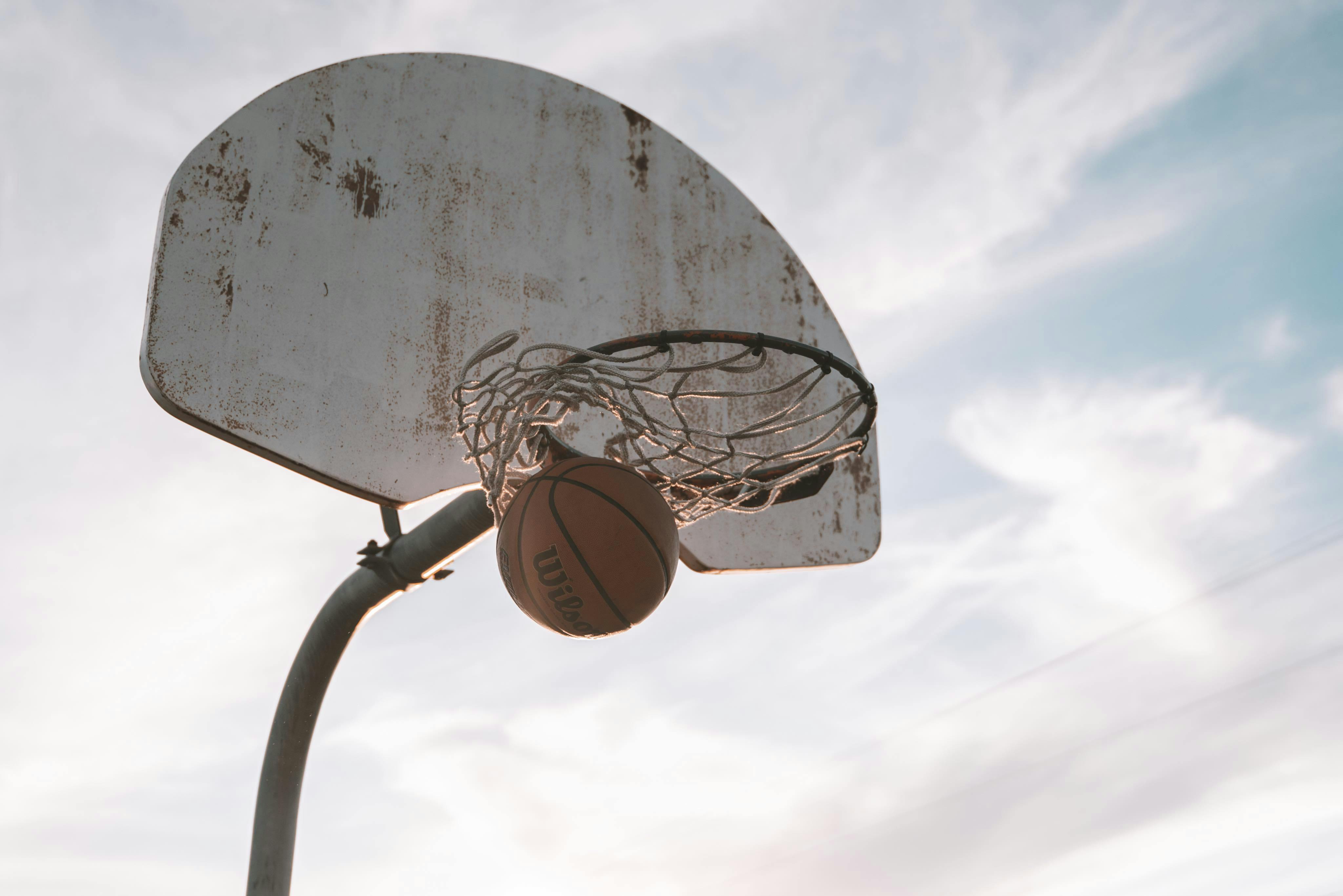 Basketball sinking into hoop against a dramatic blue sky in Ottawa, Canada.